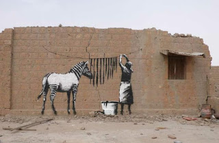 Graffiti artwork by Banksy, a zebra's black stripes are hung out to dry in the sun