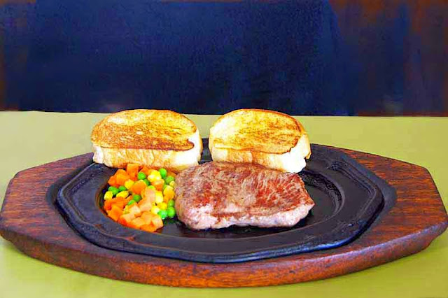 medium rare steak, bread, vegetables, metal platter