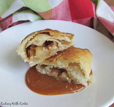 These caramel apple empanadas are easier to make than you'd think and so good. Try eating one still warm from the oven and you are sure to be hooked! caramel apple empanada cut in half with filling showing sitting on a pool of cajeta