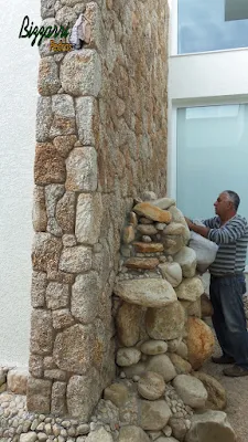 Bizzarri, da Bizzarri Pedras, fazendo os últimos reparos em lago de carpas com pedras do rio com a cascata com pedra do rio junto a parede revestida de pedra moledo em casa em condomínio em Atibaia-SP. 18 de maio de 2017.