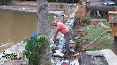 Construção do muro de pedra em volta do lago, com pedra rachão, para evitar o desmoronamento do barranco em volta do lago. Muro de pedra em Cotia-SP.