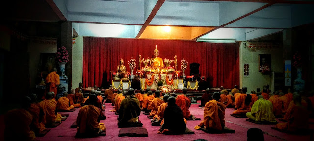 Buddhist monks reciting prayers in front of gold colored metal statue of Gouthama Buddha, Mahabodhi Society, Bangalore