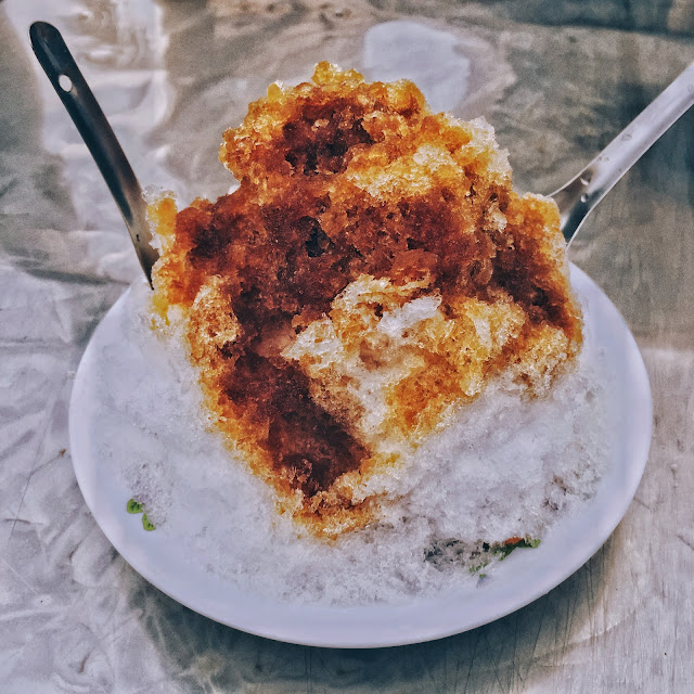 這家位在三重圖書館旁的路邊攤,提供了冰品以及各式甜品,最吸引我的是那台老舊的手動式剉冰機,老闆得從箱子裡拿出大冰磚,放上後冰塊才會開始「剉剉剉」的飛舞,飄落下的碎冰,口感比起工廠機器磨出碎冰綿密許多