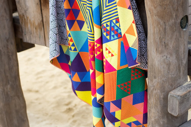 A colourful Tesalate towel hanging up to dry on a wooden structure