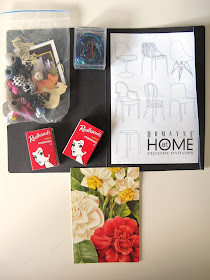 A bag of miniature items and two matchboxes on top of an event invitation and a postcard.