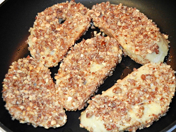 5 slices of pecan crusted french toast being cooked in a frying pan