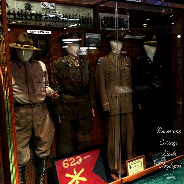 Photograph of Military Uniforms displayed in the Museum of the Barrens in a display case by Rosevine Cottage Girls