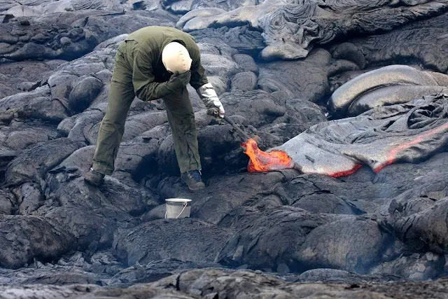 A geologist is collecting sample of molten lava from 2011 Kamoamoa eruption, at Kilauea Volcano, Hawaii, U.S.
