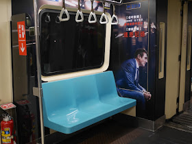 movie promotion on Taipei Metro train with image of Liam Neeson sitting next to real seats