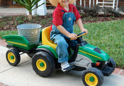a boy dressed as a farmer on a toy tractor