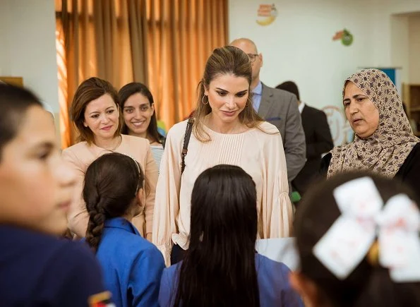 Queen Rania visited the Ballas Secondary School for Girls in Ajloun Governorate. Queen Rania style; wore Valentino blouse and Prada clutch bag