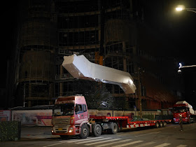 escalator hovering above a truck which delivered it to a construction site