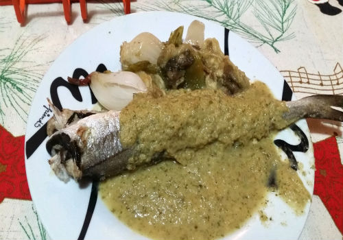 Un plato que presenta dos pescadillas con una salsa verde de hinojo por encima