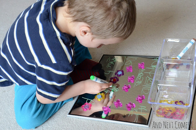 Child drawing on mirrors as part of a spring invitation to create
