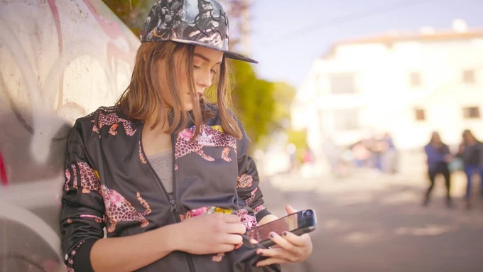 Eine stilsichere junge Frau hält ein iPhone in der Eye Android Hülle in der Hand