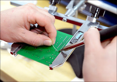 Closeup of hands soldering a circuitboard