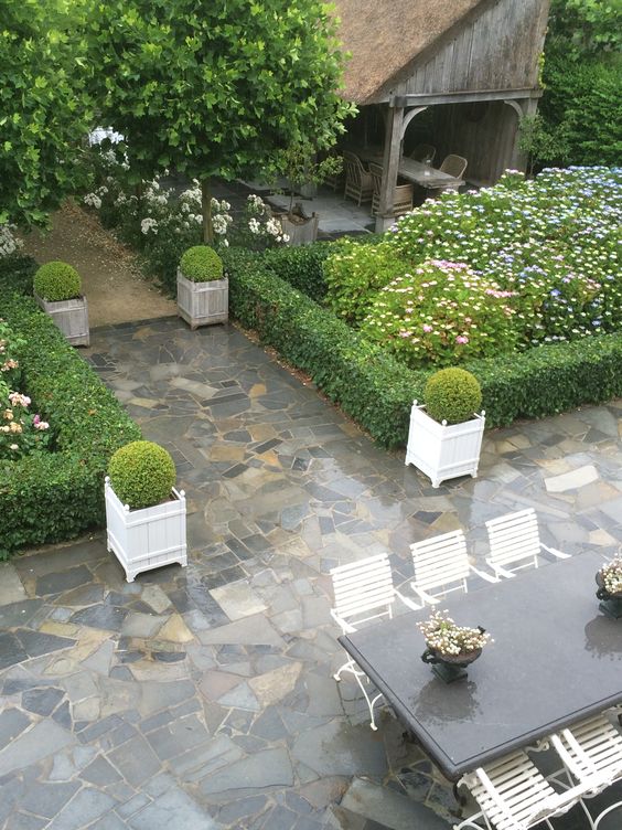 Enchanting Belgian garden with potted boxwood and stone patio at home of Greet Lefevre of Belgian Pearls.