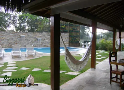 Construção da piscina em residência em condomínio em Mairiporã-SP. Piscina com a parede de pedra filete de Goiás com a cascata da piscina, os caminhos de pedra Goiás, o piso de pedra Goiás e a treliça de madeira com eucalipto tratado para esconder a caixa d'água do vizinho e a execução do paisagismo.