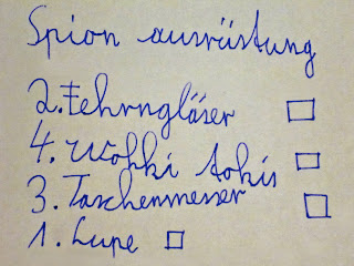 Kinderhandschrift: Spion ausrüstung 2. Fehrngläser, 4. Wokki Tokis, 3. Taschenmesser, 1. Lupe