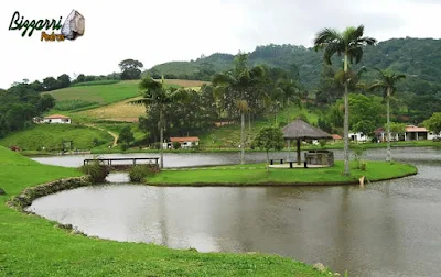 Construção de lago é com pedra moledo com a ilha e o quiosque de piaçava, churrasqueira de pedra e a ponte de pedra em sítio em Nazaré Paulista-SP.