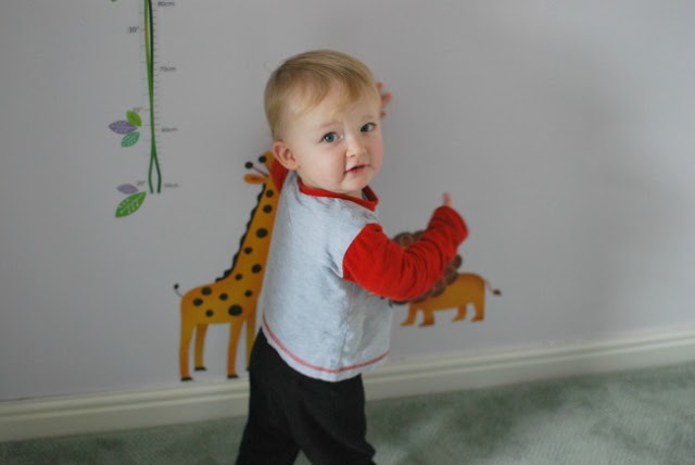 toddler looking at camera pointing to wall stickers