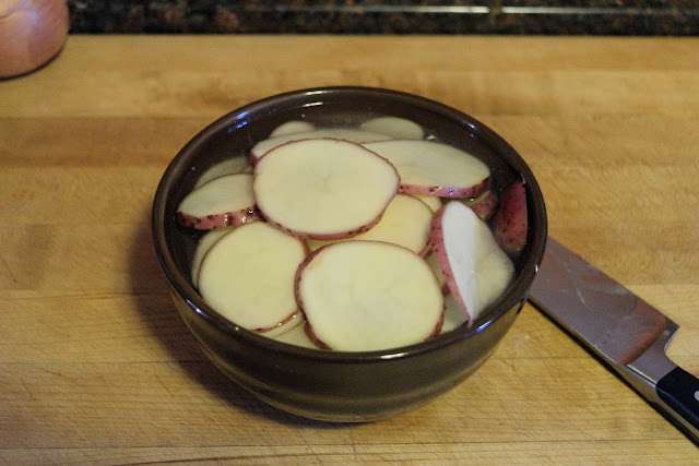 The sliced potatoes in a bowl of water. 