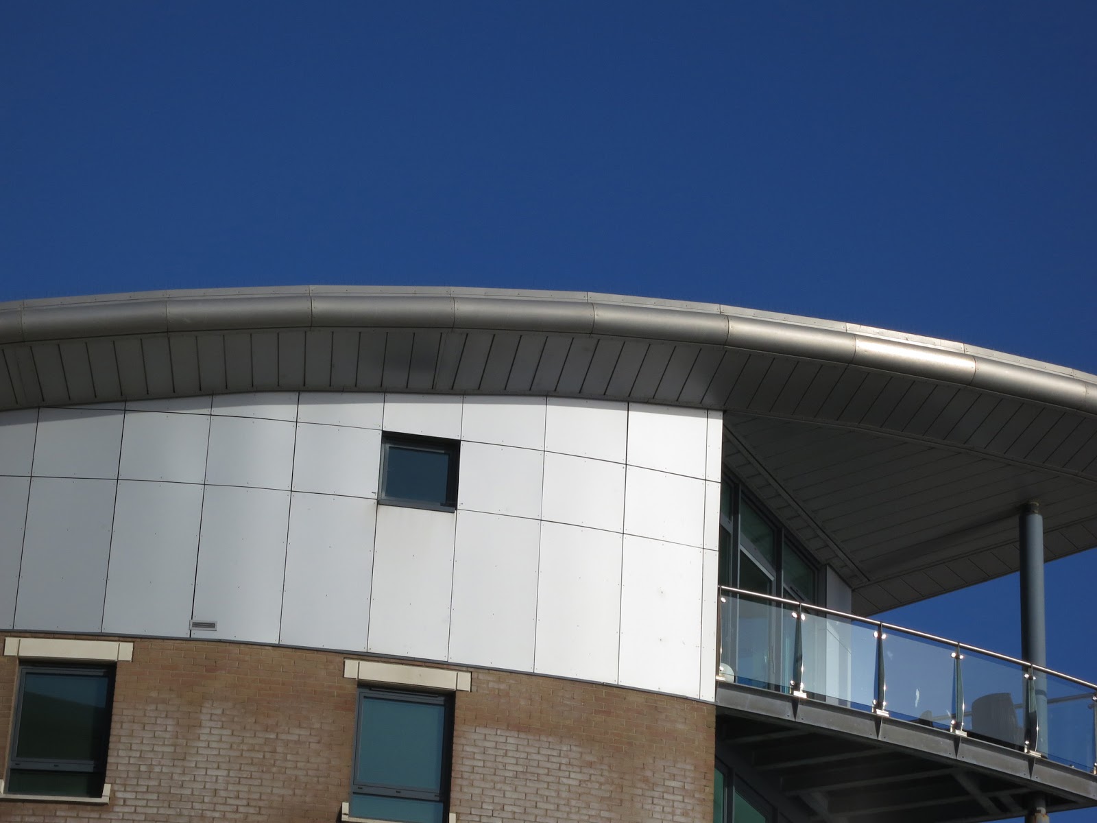 Glass balcony and curved roof against blue sky