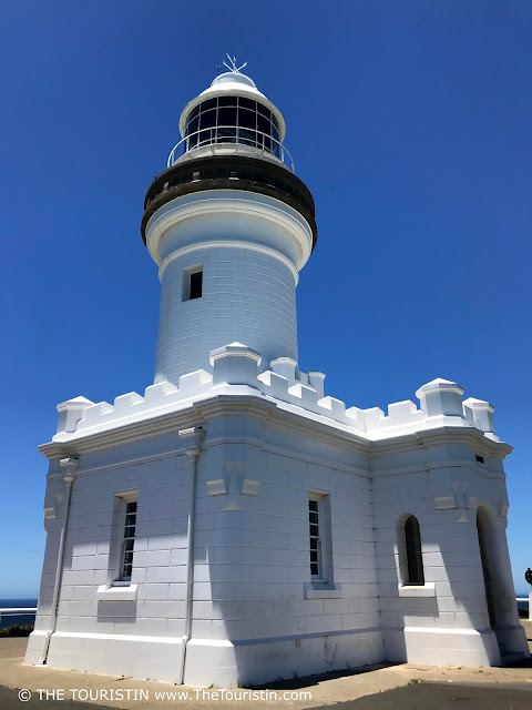 A white lighthouse under a cloudless bright blue summer sky.