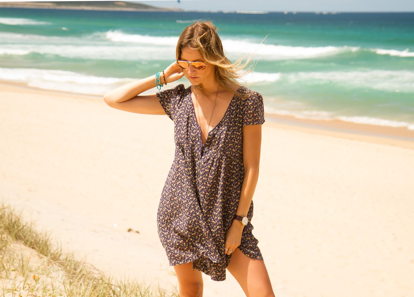 fashion and travel blogger, alison hutchinson, is wearing a floral ralph lauren dress at wanda beach in sydney, australia