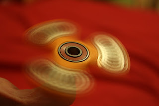 A gold fidget spinner toy spinning on someone's fingertip against a red background