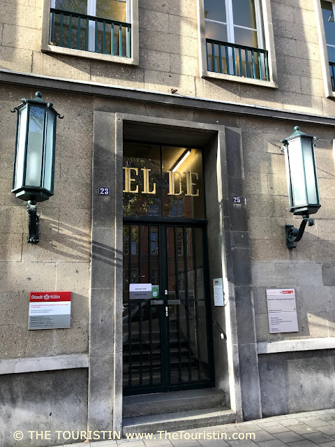 The entrance door of a grey stone property, decorated with large letters EL DE in gold.