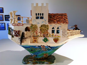 Miniature wooden painted artist's arks on display in a gallery.