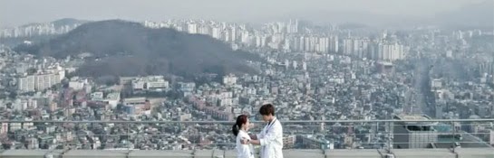 Oh Jin Hee and Oh Chang Min on the roof of the hospital with a view of the city behind them.