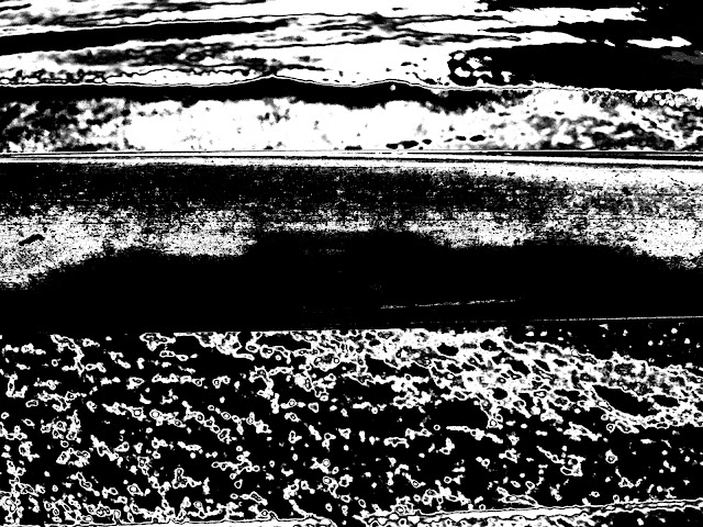 Black and white version of a metal hand-rail at West Bay in Dorset. The sea is at the top of the page, the beach at the bottom.