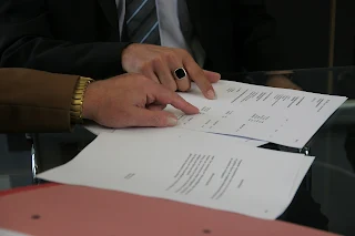 Foto imagem das mãos de um casal que vive em união estável, sobre uma mesa assinando um contrato de fiança locatícia