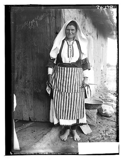 Macedonian woman in traditional costume carrying a basket with her left hand, village Negochani (Niki)