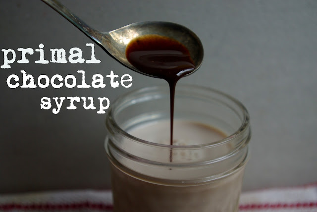 Primal paleo chocolate syrup poured into chocolate milk in a jar with antique spoon