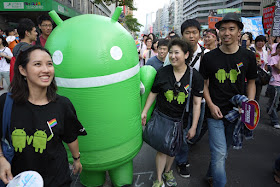 Android Robot mascot and people wearing shirts with two Android Robots holding hands and a rainbow flag at 2011 Taiwan LGBT Pride Parade