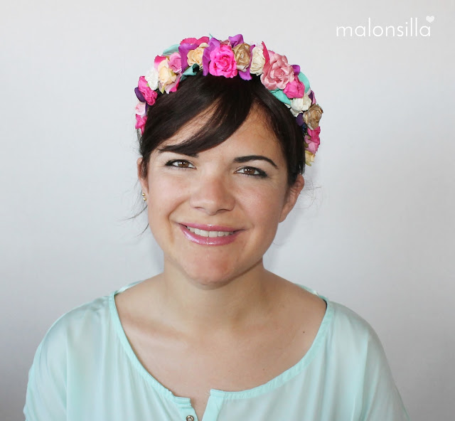 Chica de frente con look de diadema flores en varios colores, predomina el fucsia