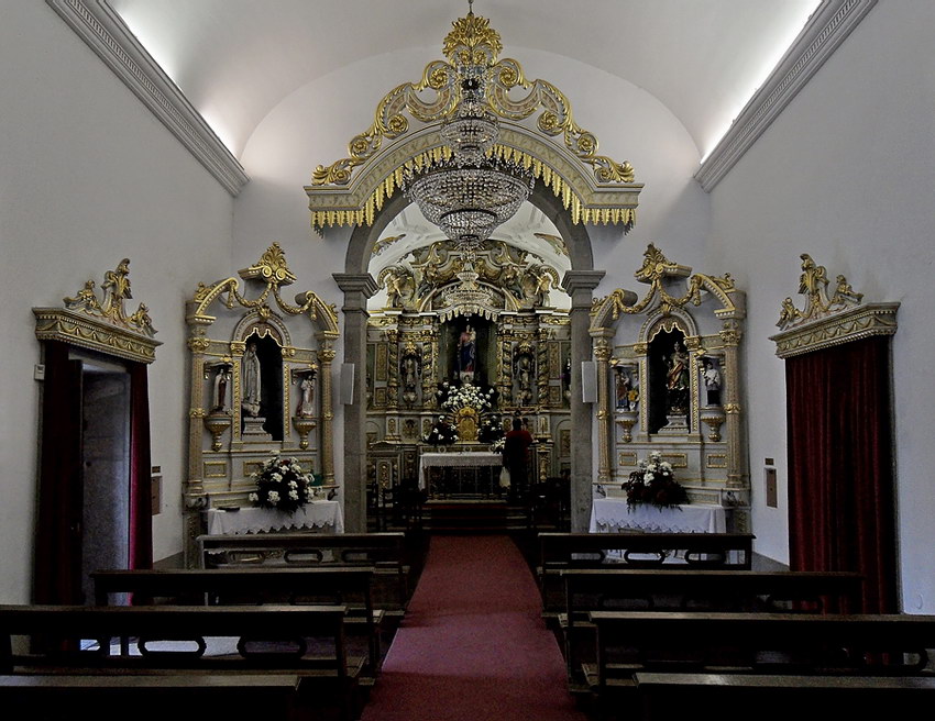 Capela Vista interior, alargada, revelando todo o altar e ainda algumas filas de bancos, embaixo