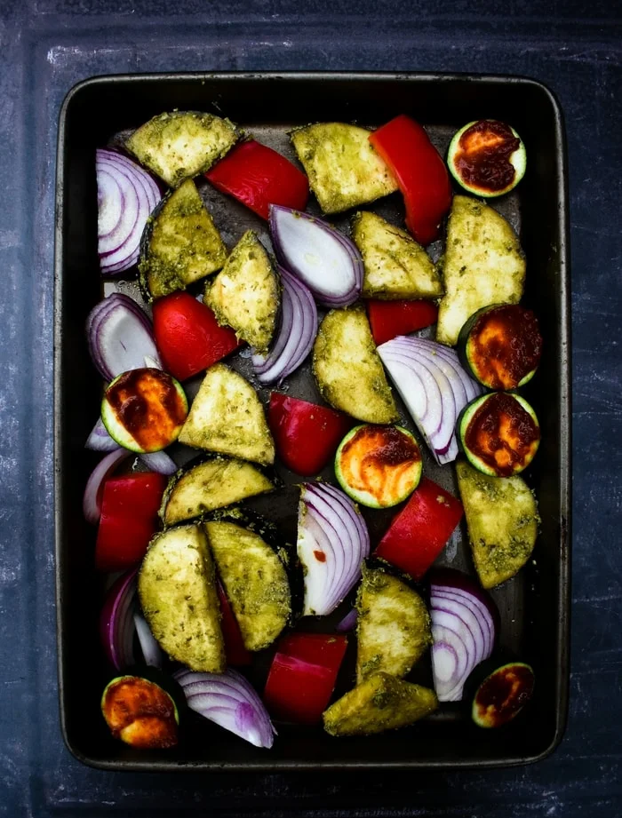 red onion, red peppers, courgette and aubergine in a roasting tray