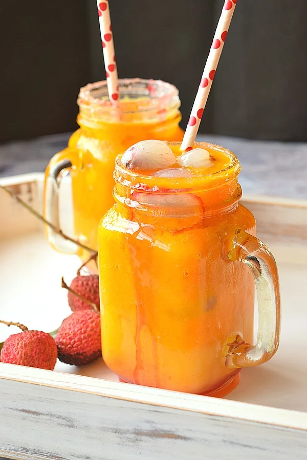 Front look of white tray having lychee fruit and mason jar having Mango Lychee Mocktail