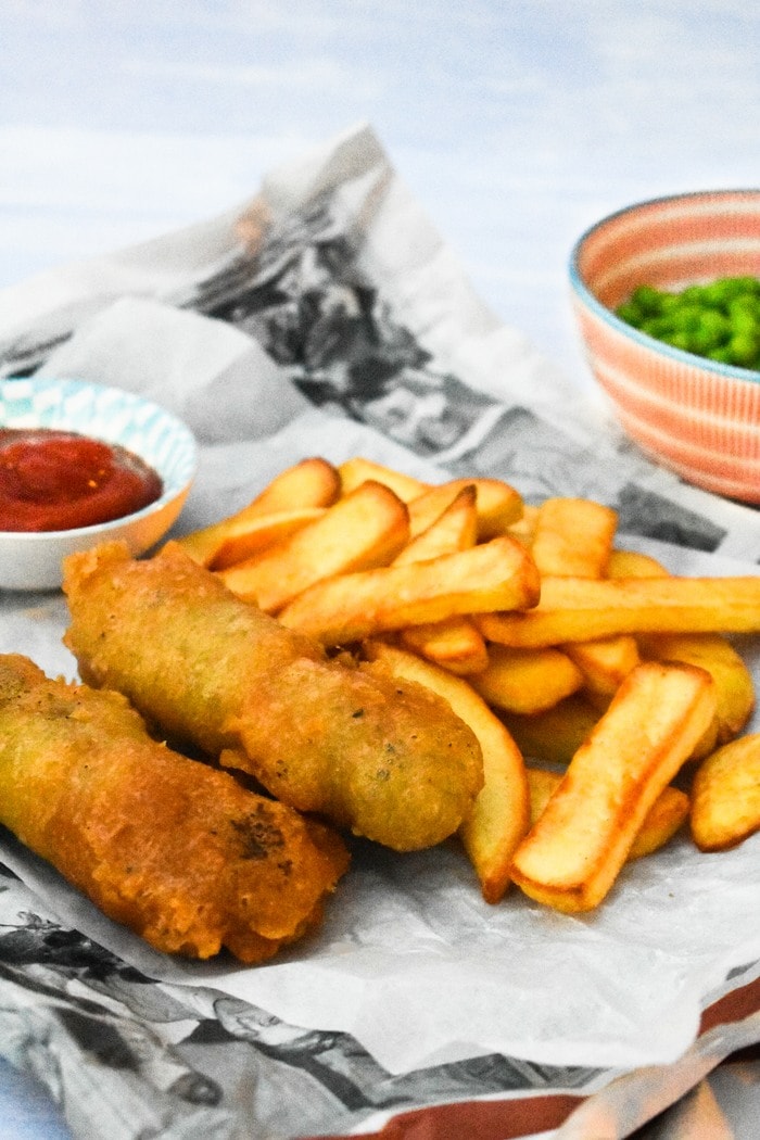 Vegan Chip Shop Sausage Supper in newspaper with chips, peas and ketchup