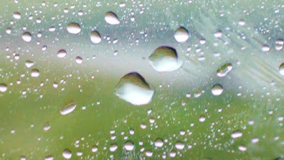 close up of rain beading on a moving car's side window