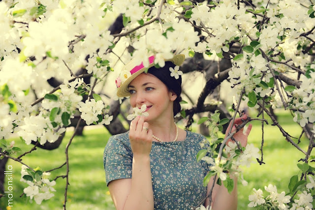 Chica de piel clara y ojos azules con sombrero de flores y almendros en flor en Moscú