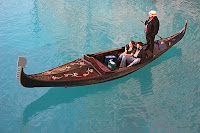 Bir Venedik kanalında gondoluyla iki turist çifti gezdiren gondolcu