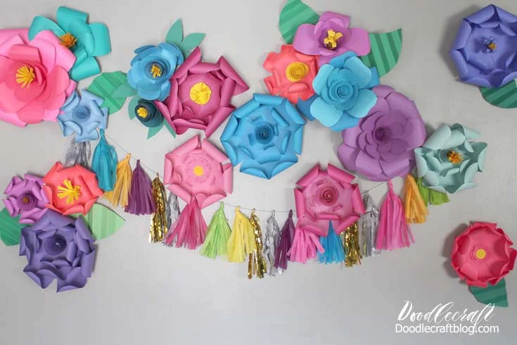 Bright colored paper flowers stuck to a wall for the perfect party backdrop.