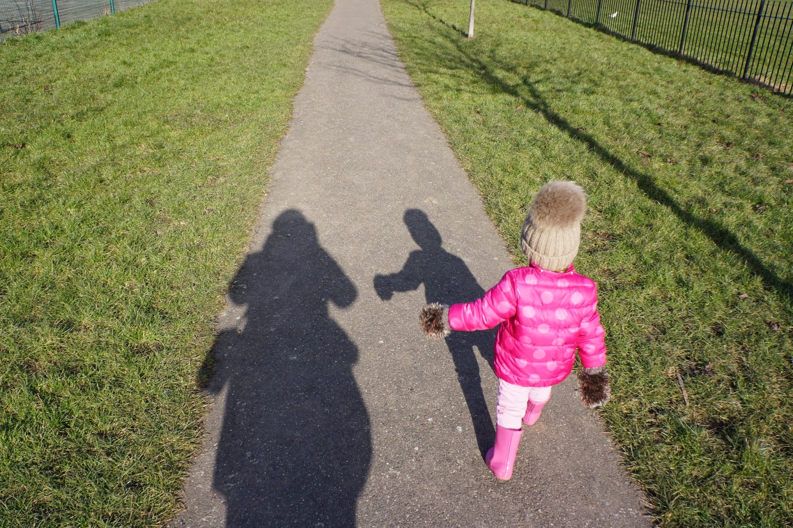 toddler girl walking at the park wearing pink puffa jacket