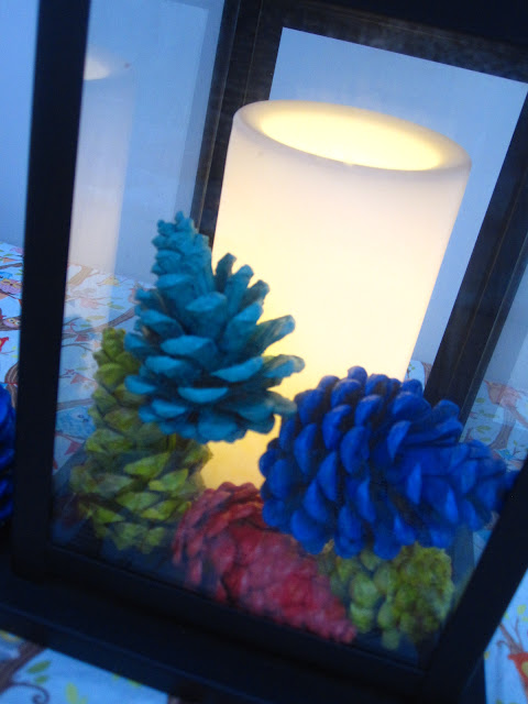 Painted pine cones in a black lantern with an led candle