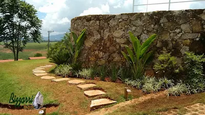 Caminho no jardim com pedra cacão de Carranca com junta de grama com a execução do paisagismo em casa em condomínio em Piracaia-SP.